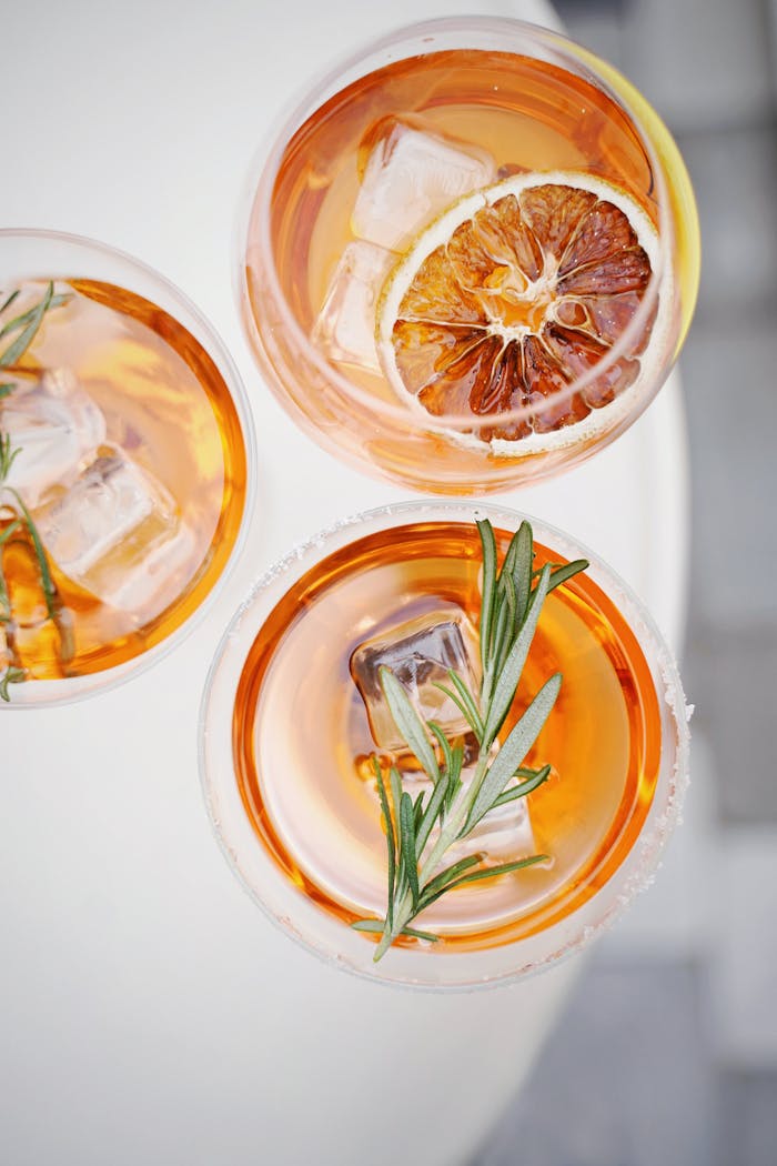 Servicios Top view of three citrus and rosemary cocktails with ice and garnish on a summer day.
