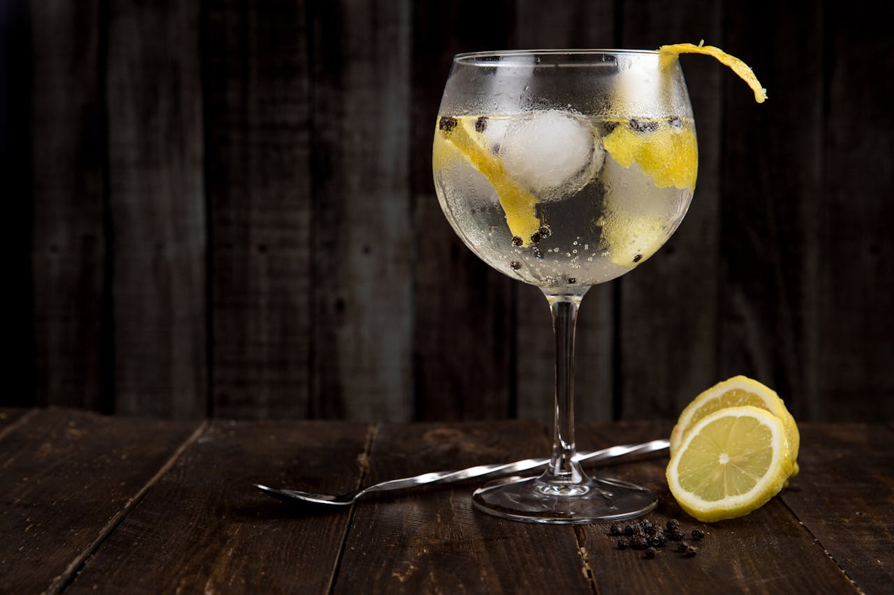 Inicio A close-up of a refreshing gin cocktail with lemon slices on a rustic wooden table, perfect for summer.